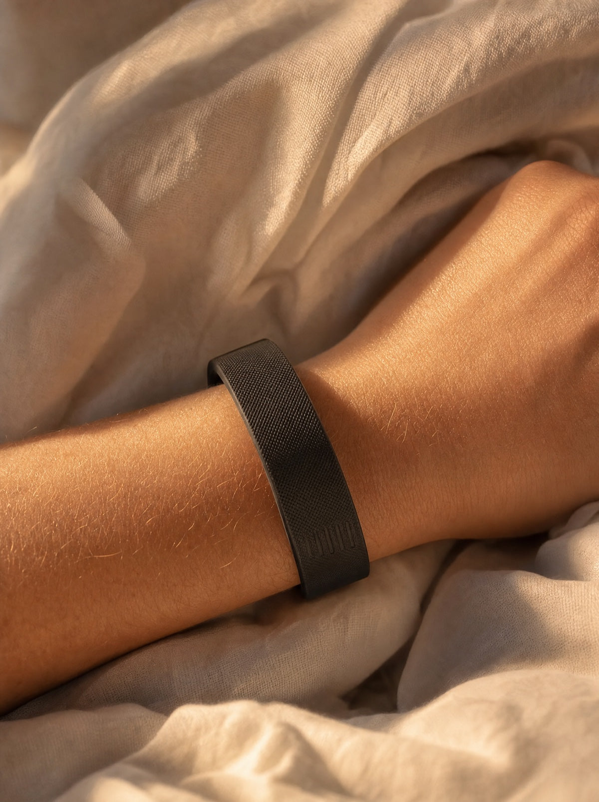 DawnPulse band on a wrist, resting in linen sheets